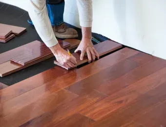 Installer setting a solid hardwood plank by hand