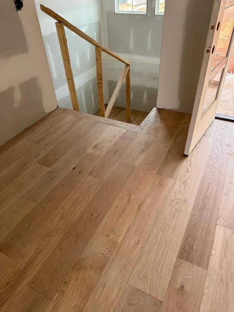 White oak floor meeting the foot of a staircase